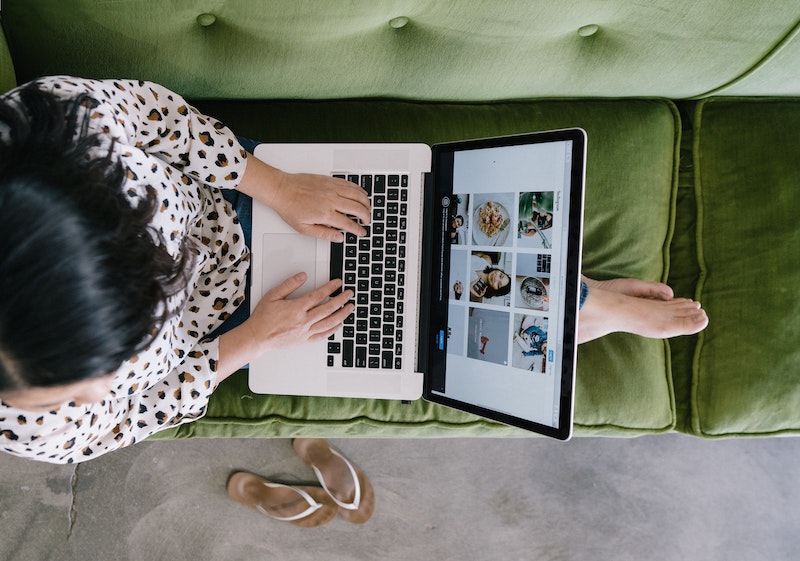 Performance metrics help to keep track of a remote team, even those who work from home. The graphic shows an aerial view of a woman who working on her laptop on a green couch.